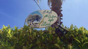 A sign with a tree and text, surrounded by greenery.