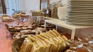 Een buffet met diverse gerechten, zoals belegde broodjes, fruit en sauzen.