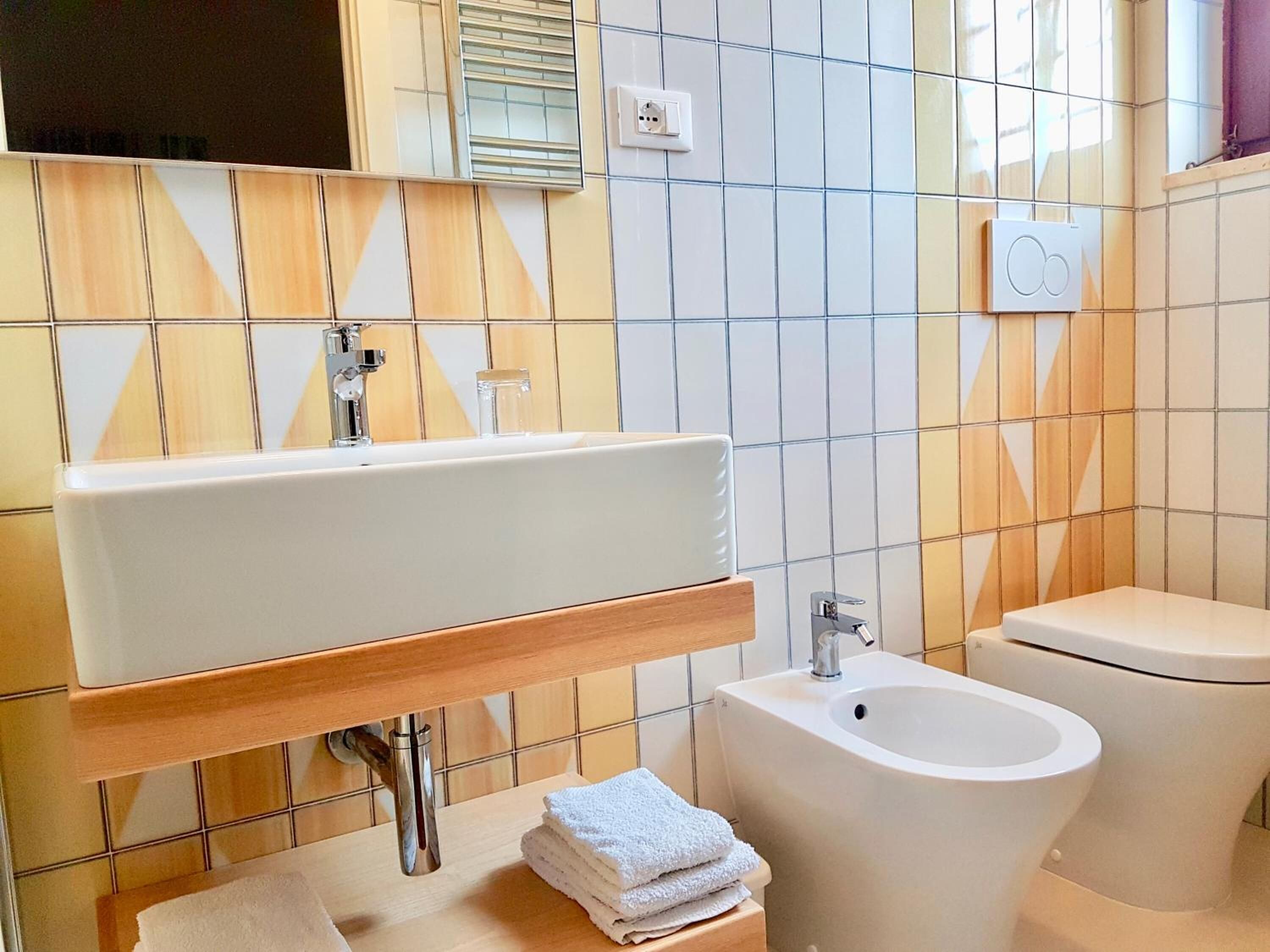 A bathroom with a rectangular sink, a bidet, and a toilet.