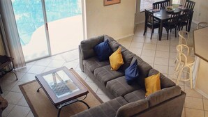 A living room with a sofa, a glass-top coffee table, and a dining area with a table and chairs. - SUMMER SALE!!! - STUNNING VILLA, LARGE PRIVATE POOL & CONSERVATION VIEWS!! (Kissimmee)