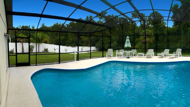 An indoor swimming pool with a clear view of the surrounding greenery and a covered seating area with chairs. - SUMMER SALE!!! - STUNNING VILLA, LARGE PRIVATE POOL & CONSERVATION VIEWS!! (Kissimmee)