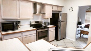 A compact kitchen with a microwave, stove, oven, and refrigerator. There is a dining table and a small seating area with a sofa. - SUMMER SALE!!! - STUNNING VILLA, LARGE PRIVATE POOL & CONSERVATION VIEWS!! (Kissimmee)