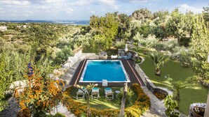 A swimming pool surrounded by a garden with various plants and a lawn. - Elisa Villa (Mylopotamos)