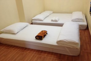 A hotel room with two single beds, each with white linens and pillows, and a rolled-up blanket on the left bed. - Bankaikow - Hostel (Kanchanaburi)