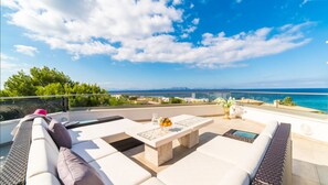 Una terrazza sul tetto con un divano bianco, un tavolino e vista mare.