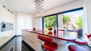 A modern kitchen with a central island, stainless steel appliances, and a large window offering a view of the outdoors. - Luxury design villa with fantastic sea and mountain views (Betlem)