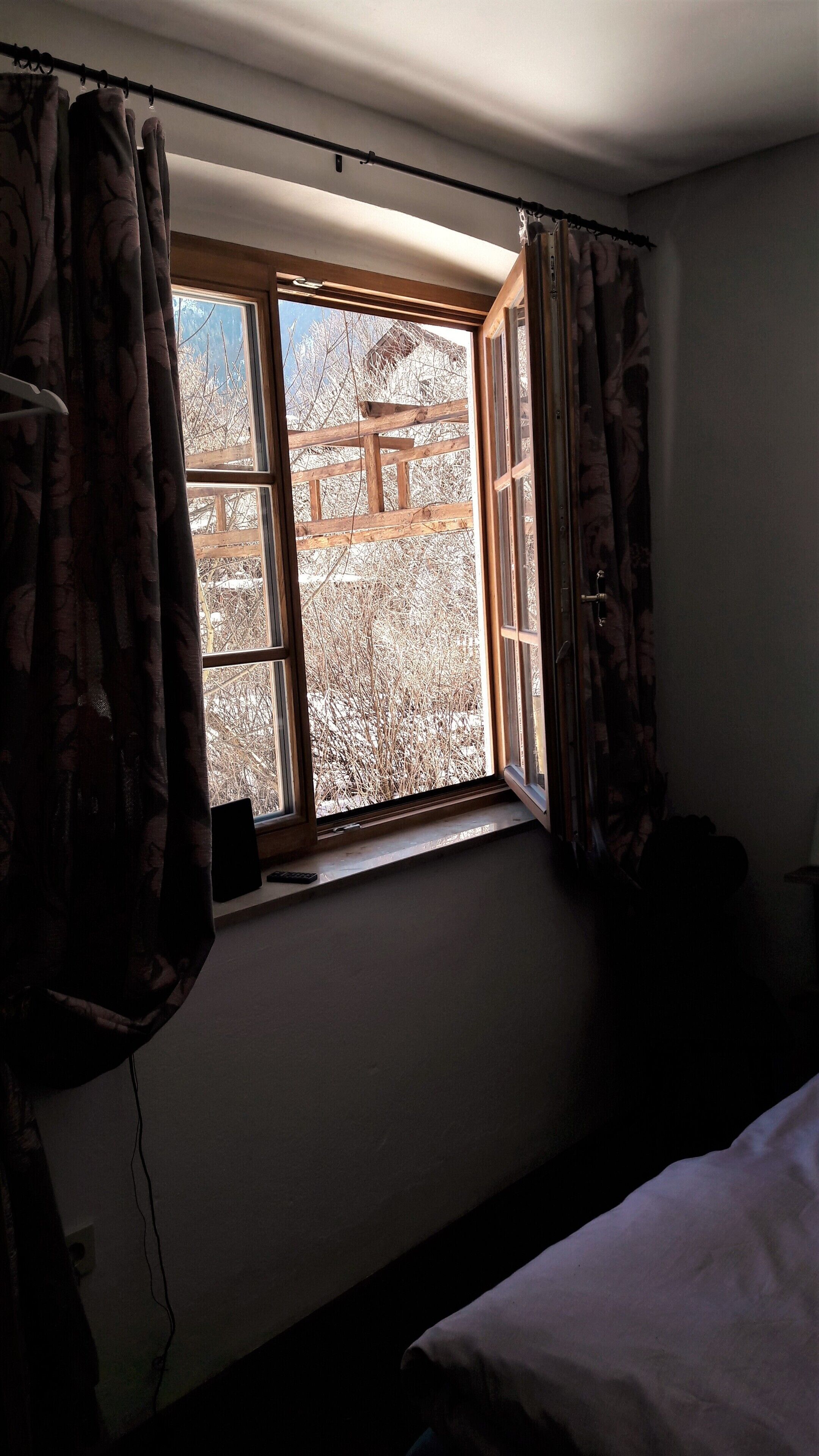 Una habitació amb finestra, cortines i un llit.