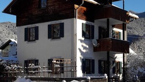 A two-story chalet with a wooden facade, a balcony, and a snow-covered roof. - 'Sissi' a charming apartment in a modern country house style (Oberammergau)