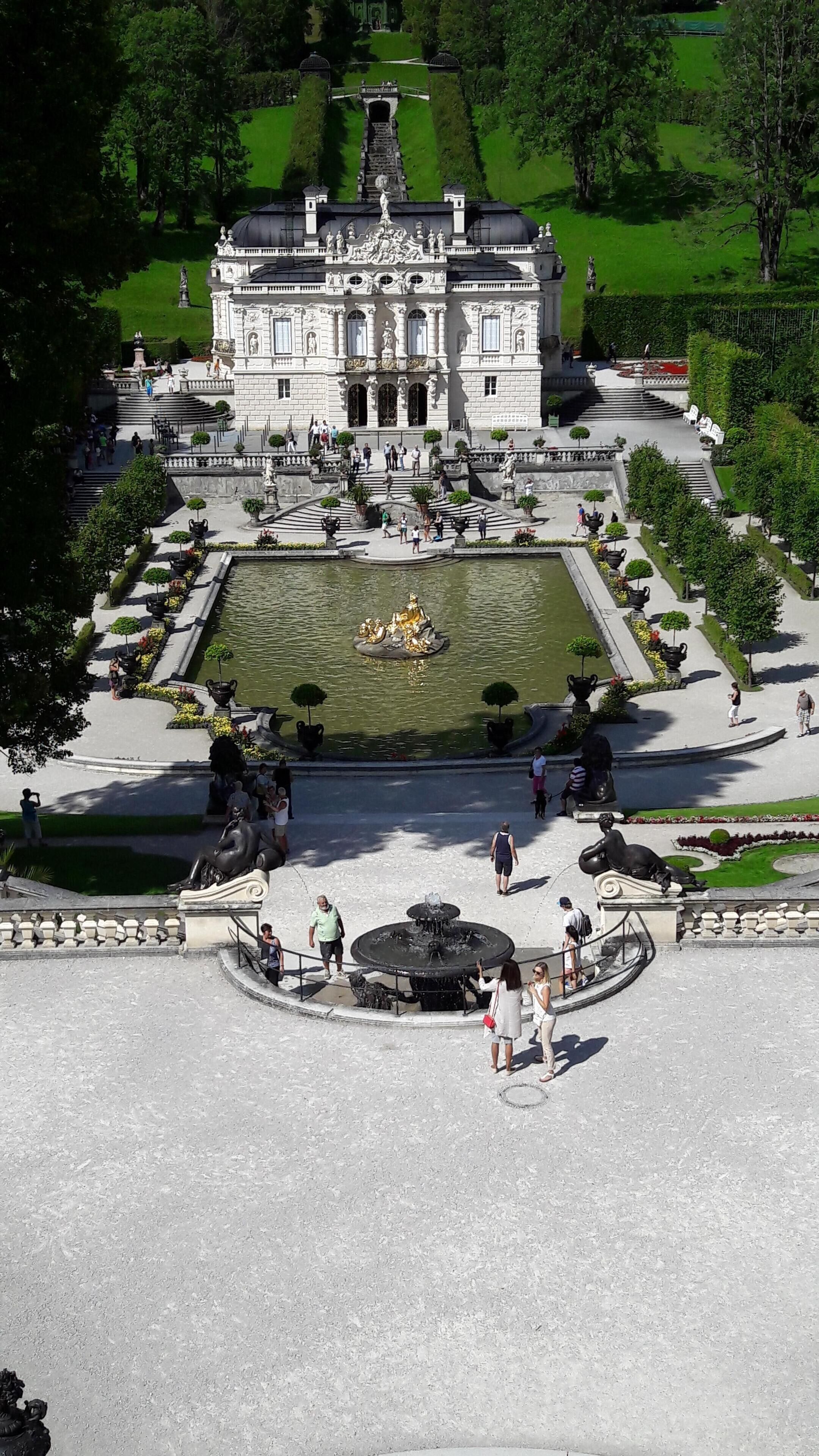 A grand building with a central fountain, surrounded by a well-manicured garden and a large open courtyard.