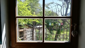 A window with a view of a garden, a wooden door, and a patterned curtain. - 'Sissi' a charming apartment in a modern country house style (Oberammergau)