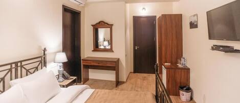 Une chambre d’hôtel équipée d’un lit, d’un bureau, d’une armoire, d’une télévision et d’une poubelle.