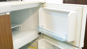 Ein weißer Kühlschrank mit klaren Kunststoffablagen und eine Mikrowelle darüber.