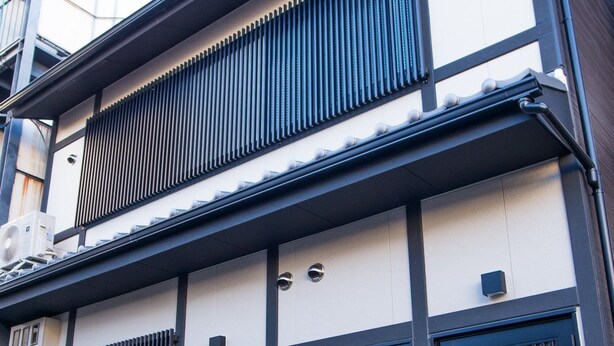 Ein traditionelles japanisches Gebäude mit Schwarz-Weiß-Fassade, das Schiebetüren und ein Ziegeldach aufweist.