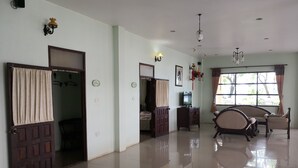 A spacious living area with a large window, a television, and a dining set. - Keerawan House Rim Khong (Phon Phisai)