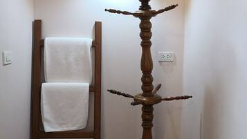 A wooden floor lamp with a light fixture, a wooden ladder leaning against a wall, and a pair of slippers on the floor.