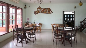 A dining area with a round table and chairs, a wall-mounted decorative piece, and a staircase leading to another level. - Keerawan House Rim Khong (Phon Phisai)