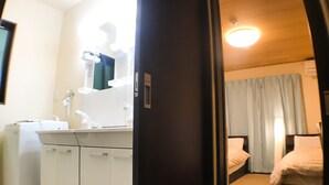 A hotel room with a bed, a desk with a chair, a washing machine, and a mirror. - One More Heart at Kamishichiken 2 (Kyoto)