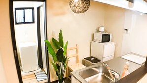 A compact kitchen with a sink, microwave, and a potted plant. - One More Heart at Kamishichiken 2 (Kyoto)