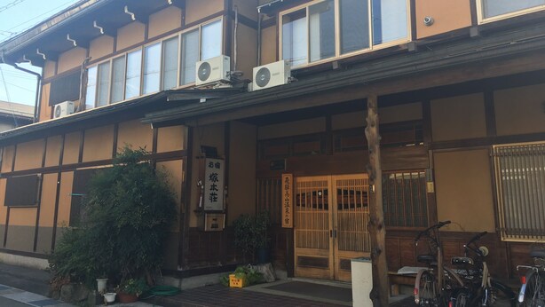 Ein traditionelles japanisches Gebäude mit Holzfassade, großen Fenstern und Klimaanlagen.