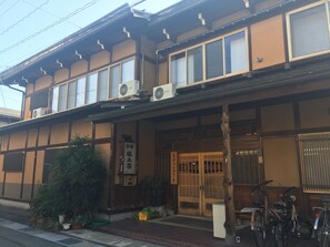 A traditional Japanese building with a wooden facade, large windows, and air conditioning units. - Oyado Tsukamotosou (Takayama)