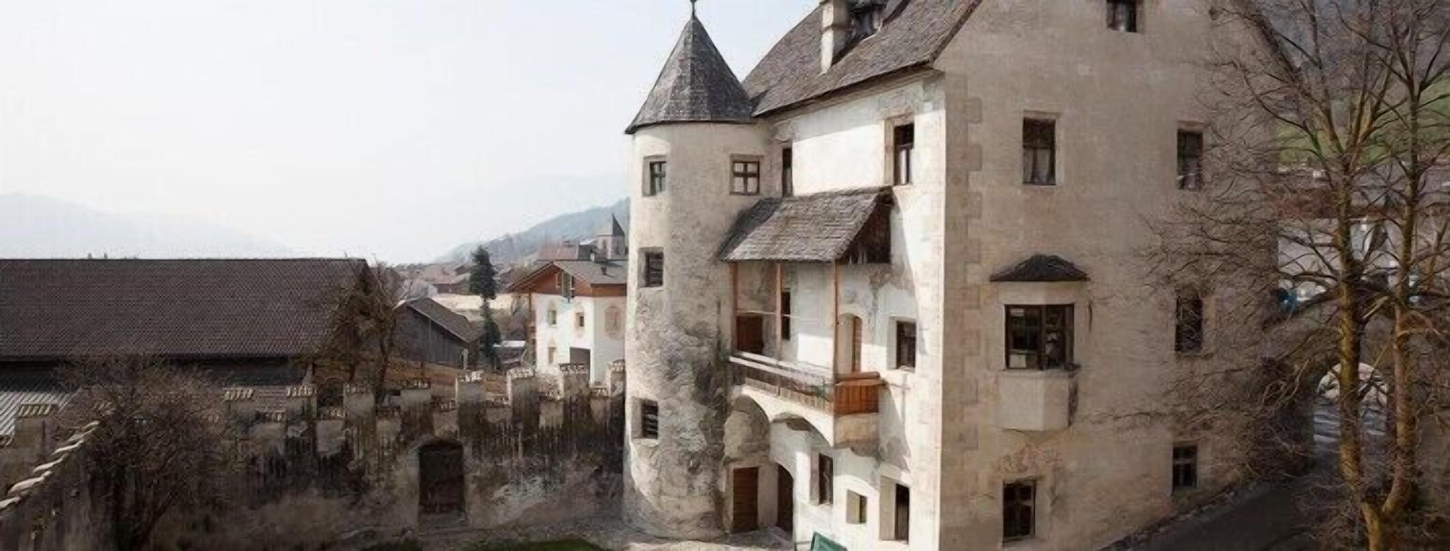 A historic building with multiple stories, a turret, and a balcony.