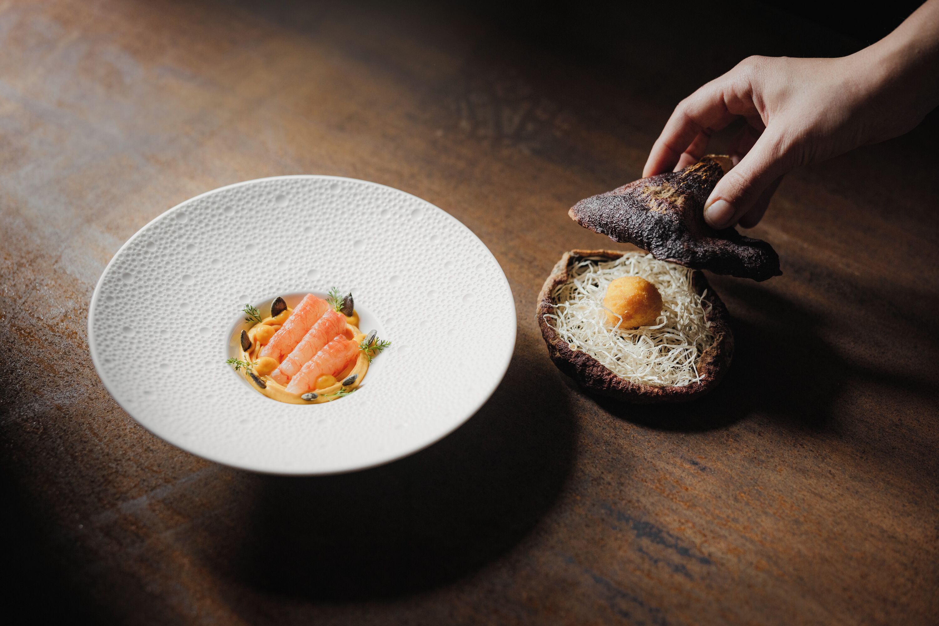 A plate with food and a hand reaching for a piece of bread.