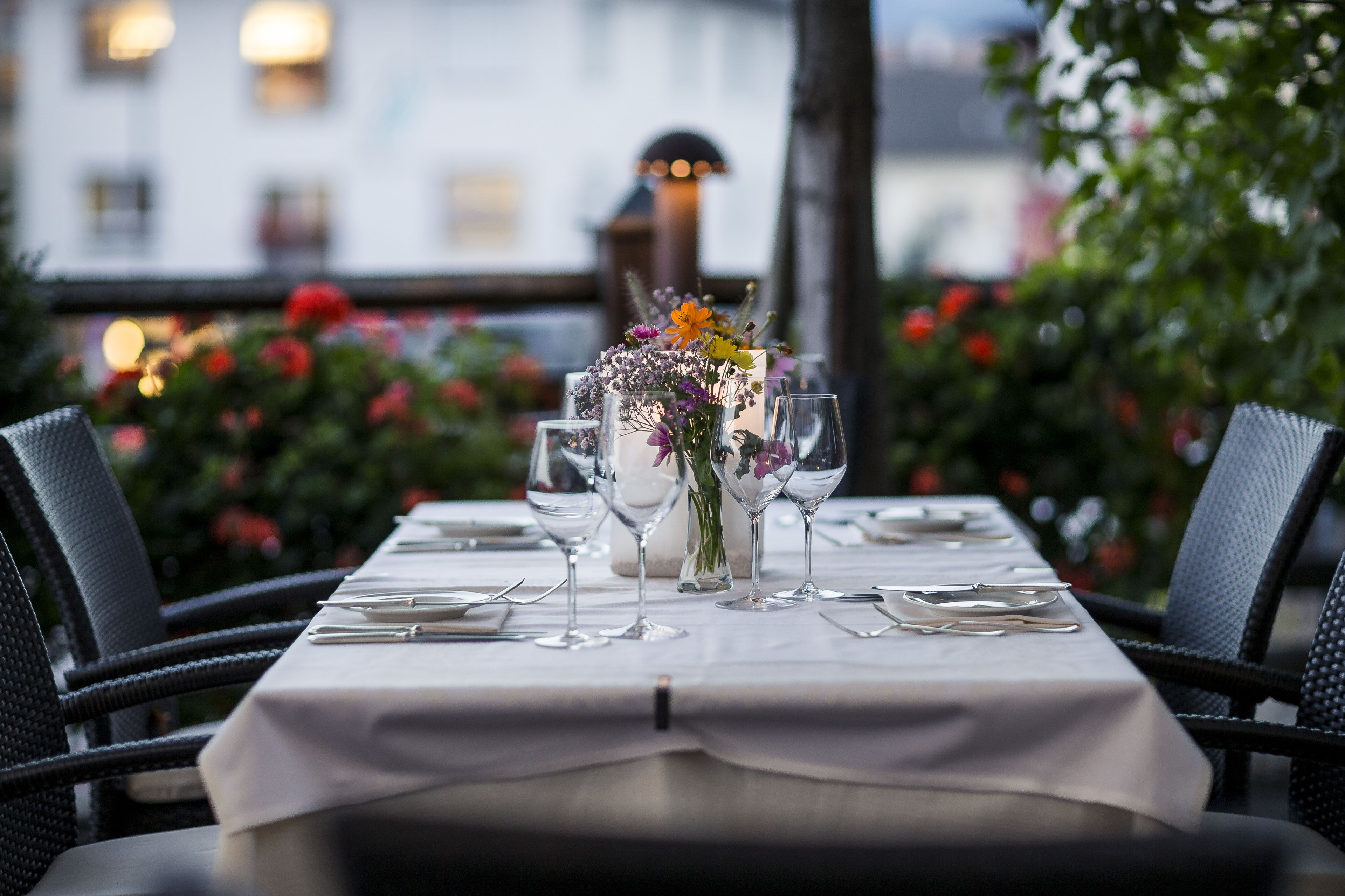 A table set for a meal with a white tablecloth, clear glassware, and a floral centerpiece.