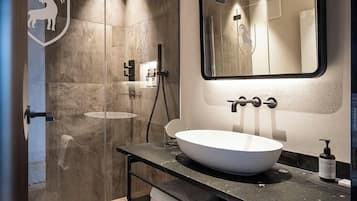 Ein modernes Badezimmer mit einer gläsernen Dusche, einem großen Spiegel und einem weißen Waschbecken.