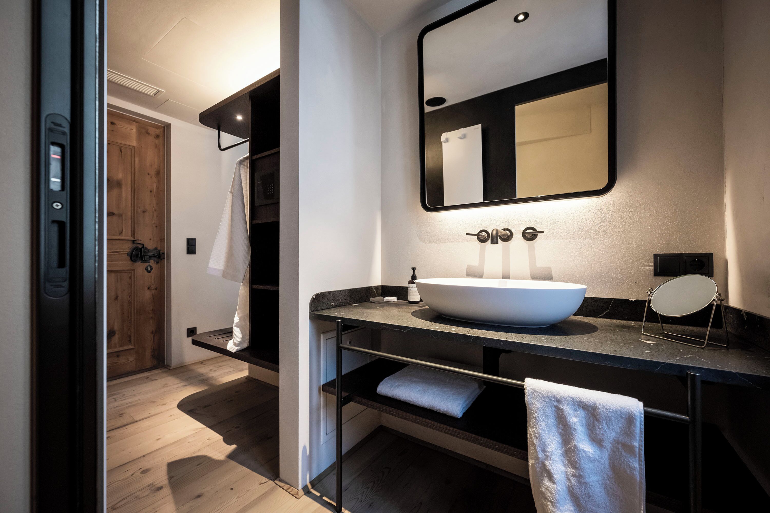 Een moderne badkamer met een groot wit wastafel, een spiegel en een handdoekrek.
