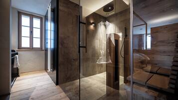 Un baño moderno con cabina de ducha de vidrio, suelo de madera y un ventanal que proporciona luz natural.