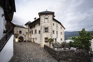 A historic building with a stone facade, a central tower, and a cobblestone courtyard. - Hotel Ansitz Steinbock (Villandro)