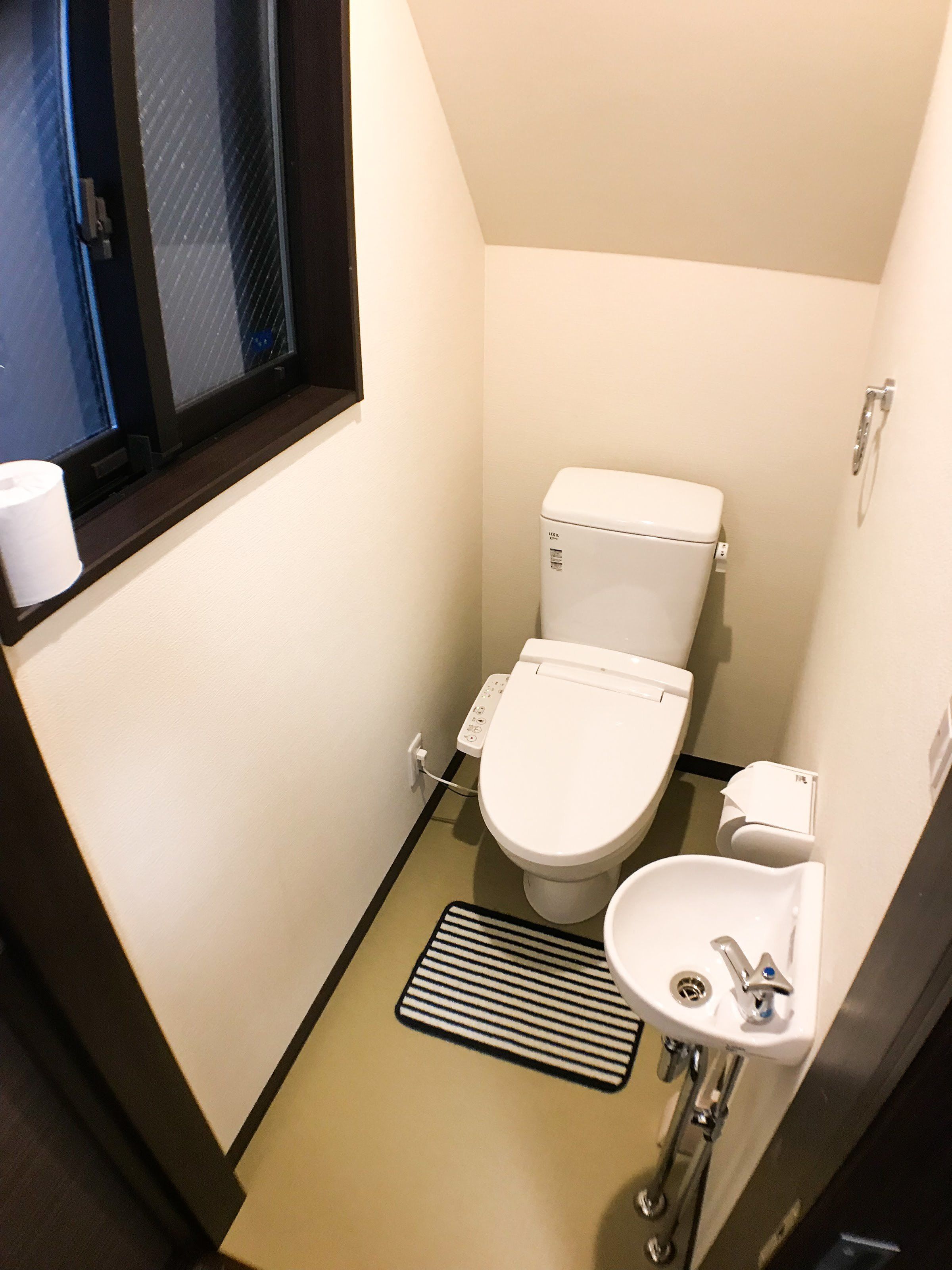 A small, compact bathroom with a toilet, sink, and window.