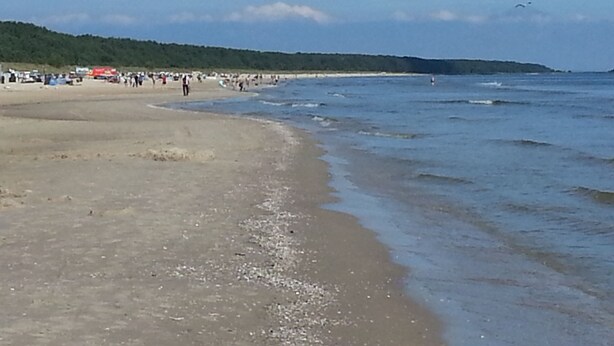 A beach with people and a red vehicle in the distance. - Modern holiday house, relax in the countryside on one level (Karlshagen)
