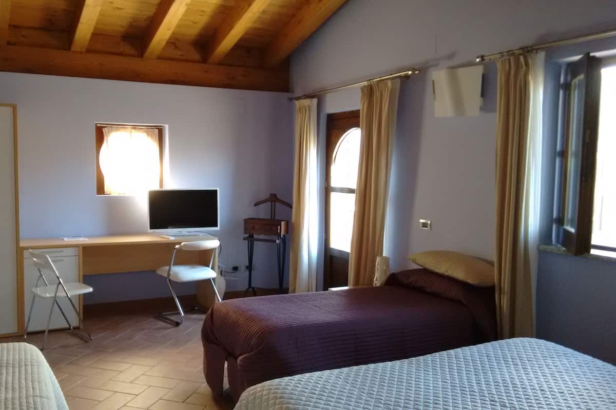A bedroom with a bed, a desk with a computer, a chair, and a wardrobe.