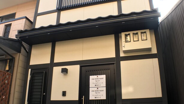 A building with a black and beige facade, a black entrance door, and a sign with Japanese text. - GH One More Heart at Toji 2 (Kyoto)