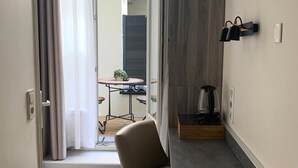A modern, compact living space with a kitchenette, a dining area, and a view of the outside. - Hôtel Les Beaux Arts (Limoges)