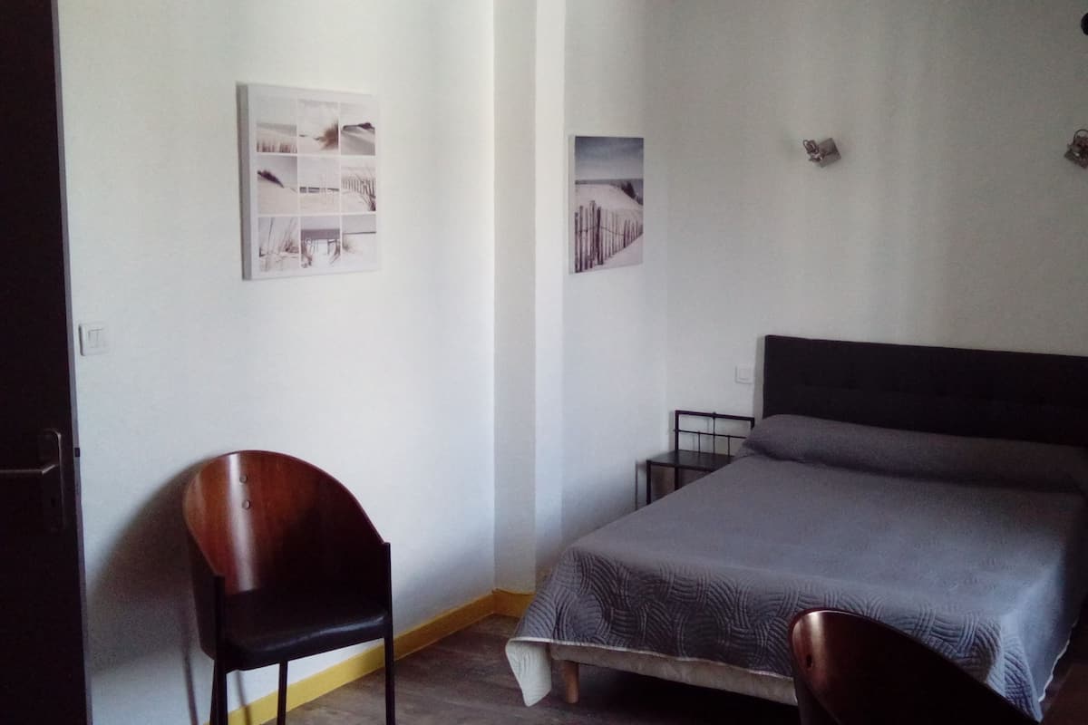 Ein Schlafzimmer mit einem Bett, einem Sessel und zwei Wandleuchten.