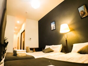 A hotel room with two beds, a nightstand, a lamp, and a framed picture on the wall. - One More Heart at Nishijin 1 (Kyoto)