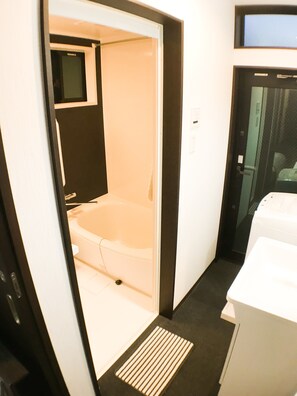 A bathroom with a bathtub, a toilet, and a washing machine.