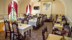A dining area with multiple tables and chairs, arranged in a semi-circular fashion. - Hotel Astoria (Satu Mare)