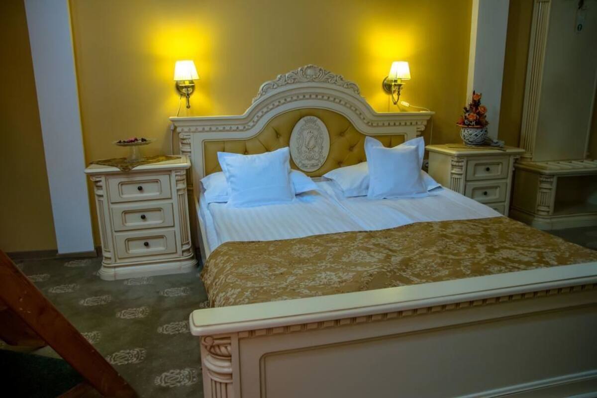 A bed with a tufted headboard, two bedside tables with lamps, and a floral arrangement on one table.
