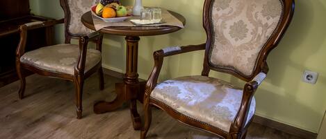 A dining area with two ornate wooden chairs and a round table.