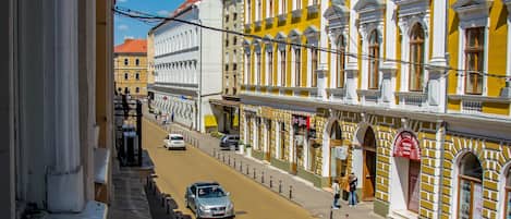 A street view with yellow buildings, a clear sky, and a few cars on the road.
