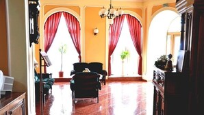 A spacious lobby with red curtains, a chandelier, and a piano. - Hotel Astoria (Satu Mare)