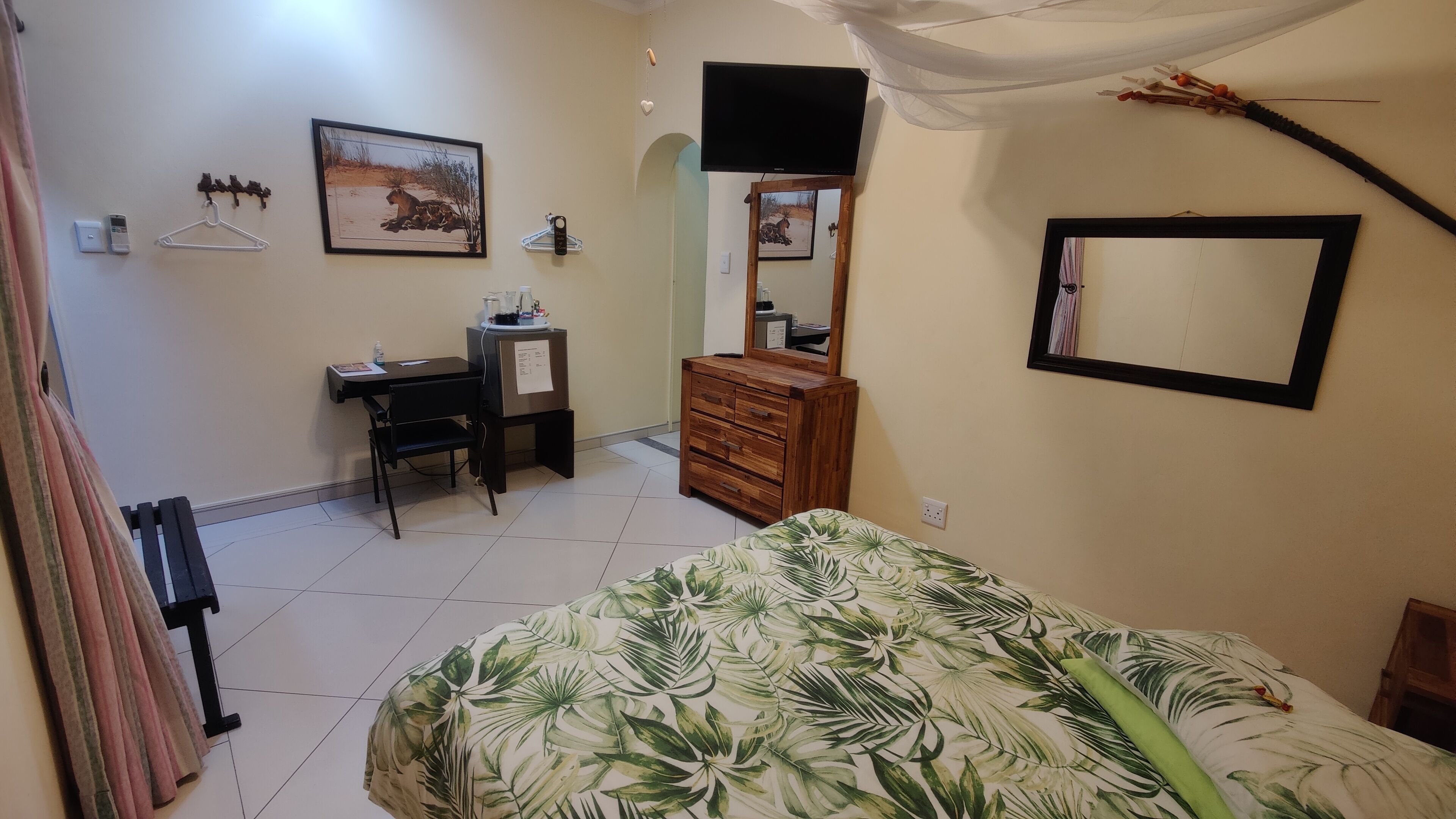 Un dormitorio con cama, escritorio, cómoda y espejo.