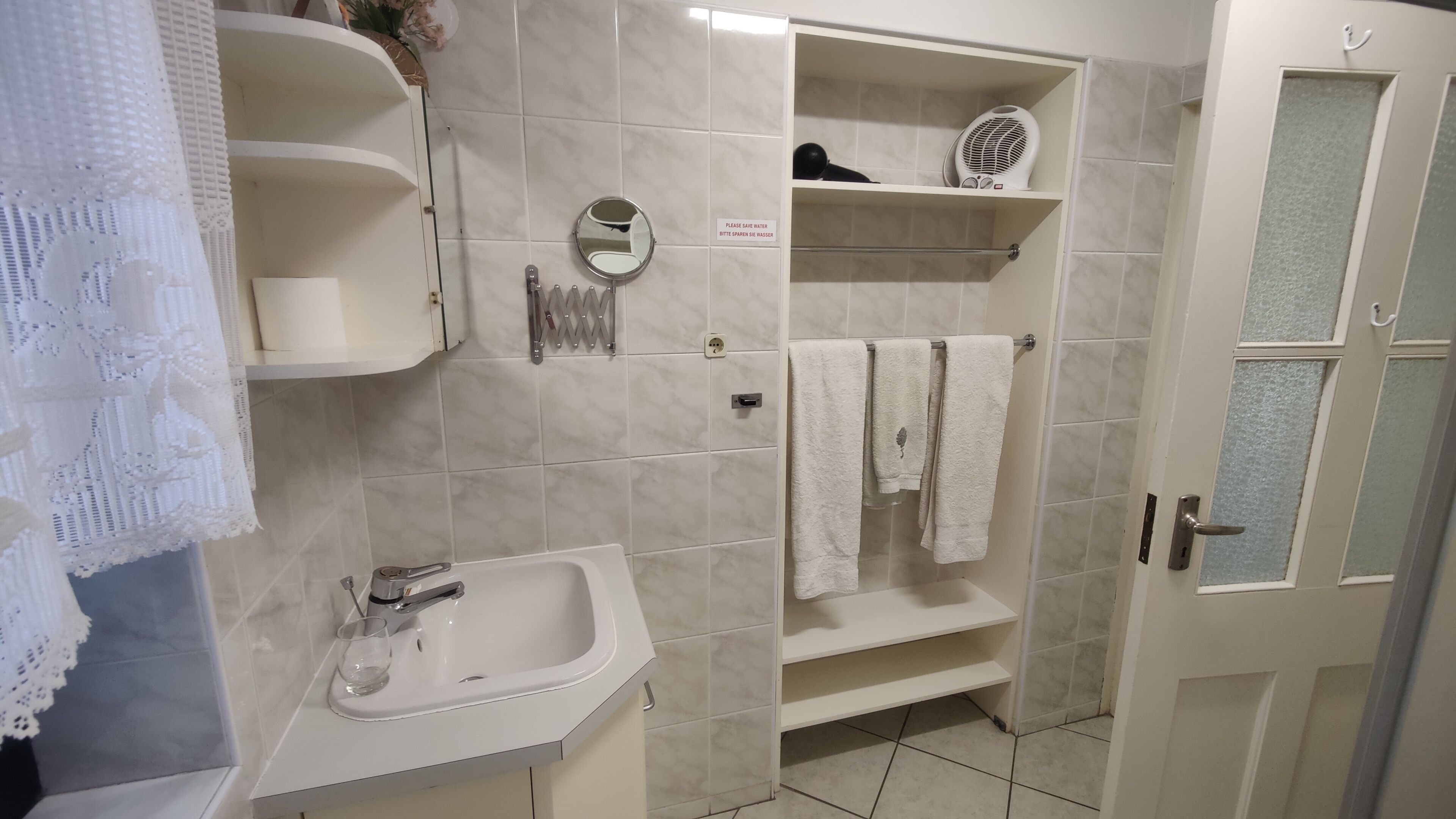 Une salle de bain équipée d’un lavabo, d’un miroir, d’un porte-serviettes et d’étagères.