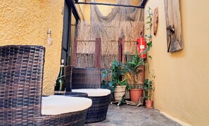 A narrow outdoor seating area with wicker furniture and potted plants. - Maison Ambre Guesthouse (Windhoek)