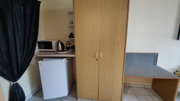 A compact kitchenette with a microwave, kettle, and refrigerator.