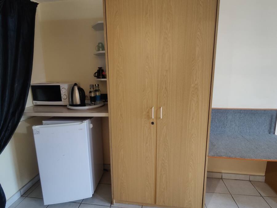 A compact kitchenette with a microwave, kettle, and refrigerator.