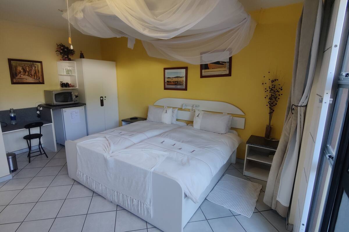 A hotel room with a bed, a desk with a microwave, a small refrigerator, and a cabinet.